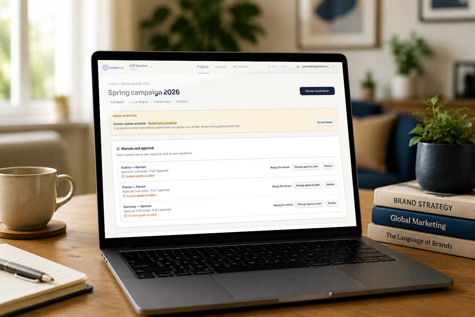 A laptop on a desk showing the Localizethat project overview for “Spring campaign 2026” — one content item across three markets, each listed as ready for review
